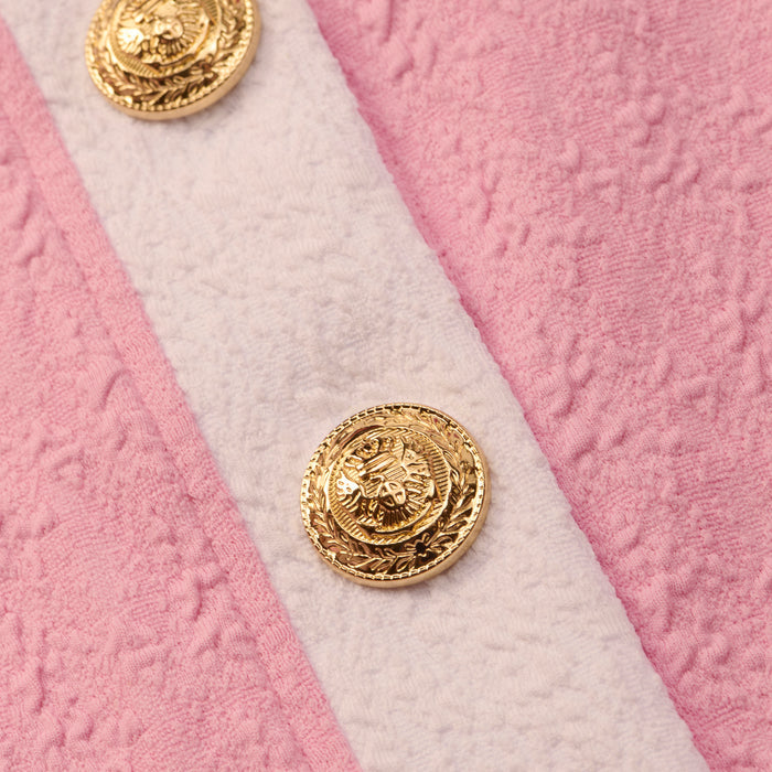 Close-up of the Adaline Cardigan Cover-Up’s textured pink fabric with a white stripe, showcasing ornate gold embossed buttons—an ideal detail for the perfect beach-to-boat swimsuit cover-up.