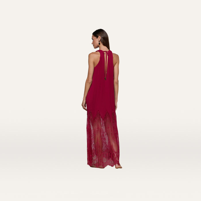 Barefoot and facing away, a woman models the Adalynn Cover-Up Dress—a sleeveless, floor-length red chiffon piece with delicate lace details—set against a plain white background; the perfect resort dress for your next getaway.