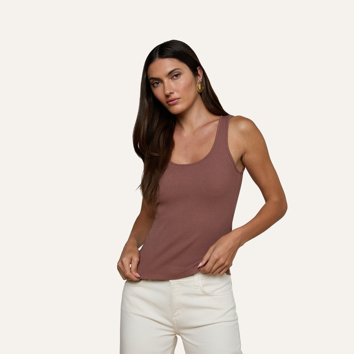 A woman with long brown hair wears the Adira Scoopneck Tank in brown and white pants, standing against a plain light background and looking at the camera.