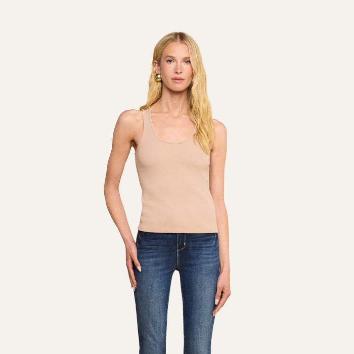 A woman with long blonde hair wears the Adira Scoopneck Tank in beige, paired with blue jeans, standing against a plain light background and looking at the camera with a neutral expression.