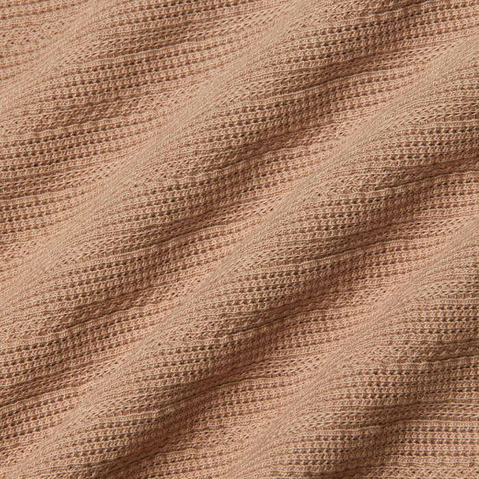 Close-up of the Adira Scoopneck Tank in peach-colored organic cotton, featuring a ribbed, textured pattern in diagonal lines. The soft material is slightly stretched, highlighting the details of the individual knit stitches.