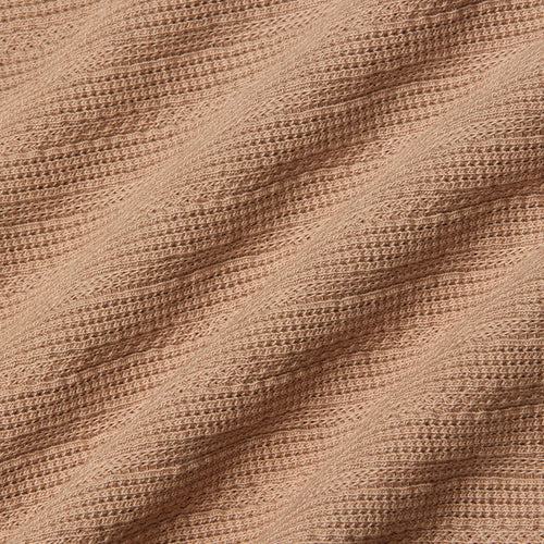 Close-up of the Adira Scoopneck Tank in peach-colored organic cotton, featuring a ribbed, textured pattern in diagonal lines. The soft material is slightly stretched, highlighting the details of the individual knit stitches.