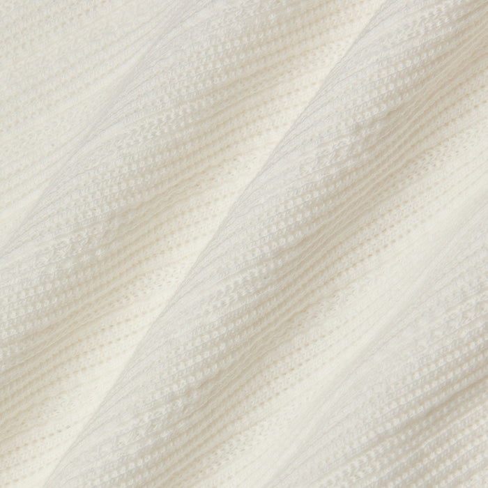 Close-up of the Adira Scoopneck Tank in white ribbed knit cotton pointelle fabric, featuring diagonal lines and textured patterns, with soft folds that create a cozy appearance.