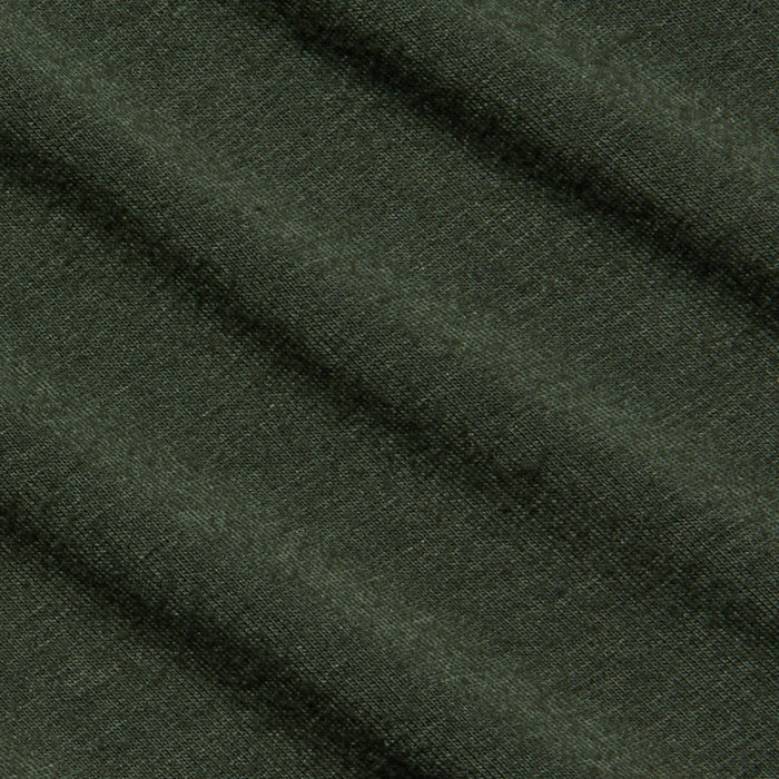 Rich dark green fabric of the Aja Turtleneck, featuring a soft knit texture and diagonal folds that create gentle shadows and highlights across its surface.