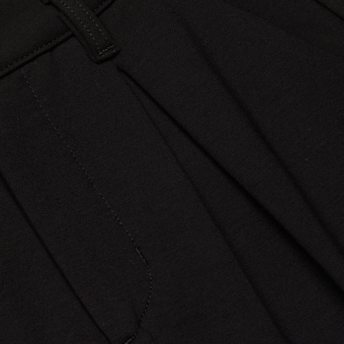 Close-up of the Akasha Bermuda Short in black stretch ponte fabric, featuring a seam, waistband with a belt loop, and pleated detailing.