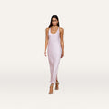 A woman wearing the Akiya Satin Maxi Dress in pastel lilac and strappy heels walks confidently against a plain white background.