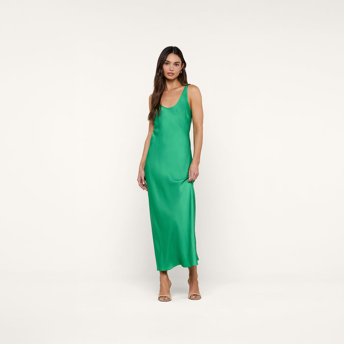 A woman stands against a white background wearing the Akiya Satin Maxi Dress in a sleeveless, island green bias-cut silhouette paired with open-toe heels.