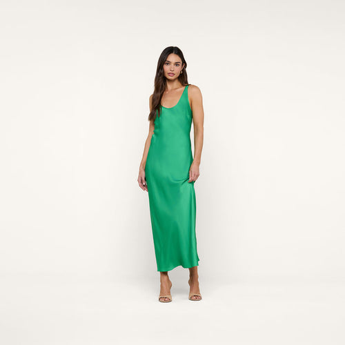 A woman stands against a white background wearing the Akiya Satin Maxi Dress in a sleeveless, island green bias-cut silhouette paired with open-toe heels.