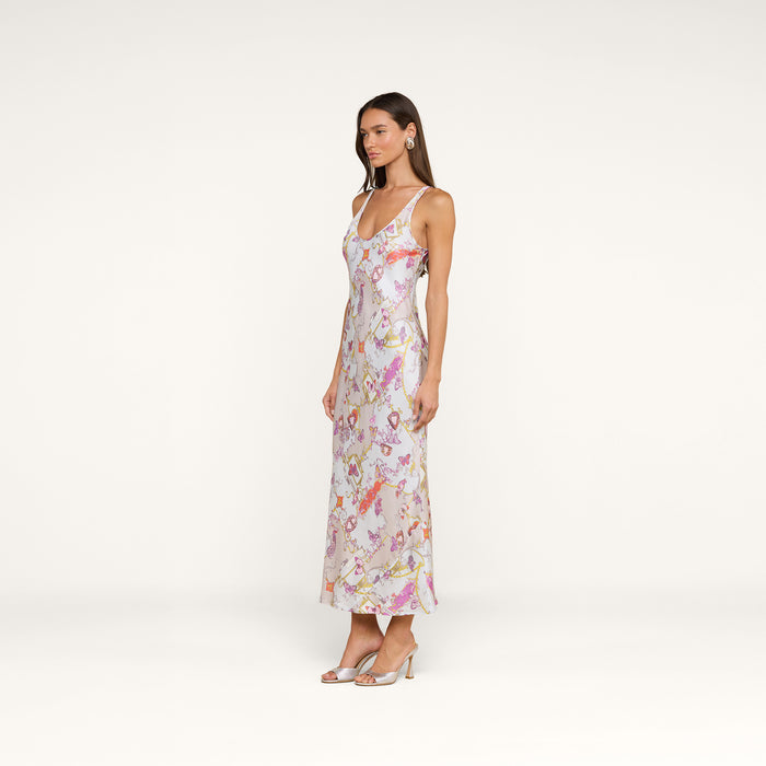 Woman in the Akiya Satin Maxi Dress—a sleeveless, floral-print, ankle-length piece with spaghetti straps—paired with open-toe heels, standing against a plain white background.