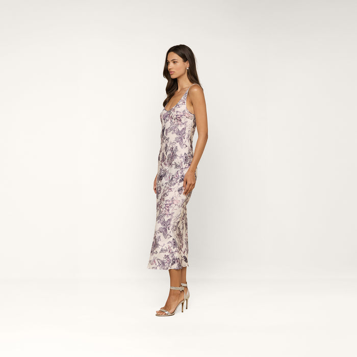 A woman in the sleeveless Akiya Satin Maxi Dress stands sideways against a plain white background, paired with high-heeled sandals.