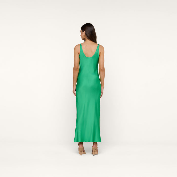 A woman stands facing away against a plain white background, wearing the sleeveless, ankle-length Akiya Satin Maxi Dress in island green paired with beige heels.
