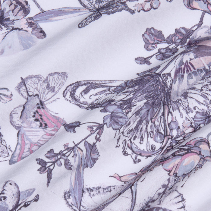 Close-up of fabric with a delicate butterfly and floral pattern in soft purple, gray, and pink tones, showing gentle folds and texture—perfect for creating the Akiya Satin Maxi Dress or a bias-cut satin garment.