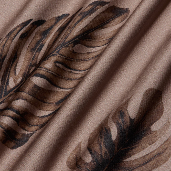 Close-up of the Akiya Satin Maxi Dress in beige, featuring a brown palm leaf print, with soft folds and a smooth, bias-cut satin texture.
