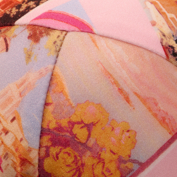 Close-up of the Alexandria Bikini Top, featuring colorful, patterned fabric with abstract shapes and floral prints in shades of pink, yellow, and orange—reminiscent of a vibrant postcard print—and detailed stitched seams.