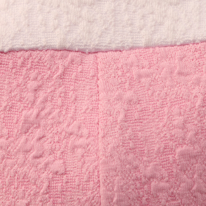 Close-up of a textured pink towel with a white towel on top, showing visible fabric patterns and vertical stitching down the center of the pink towel—details that evoke the meticulous construction seen in the Alexandria Bikini Top or in garments made from textured bouclé fabric.