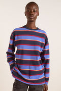 Person wearing a striped sweater with blue, red, and yellow colors on a plain background