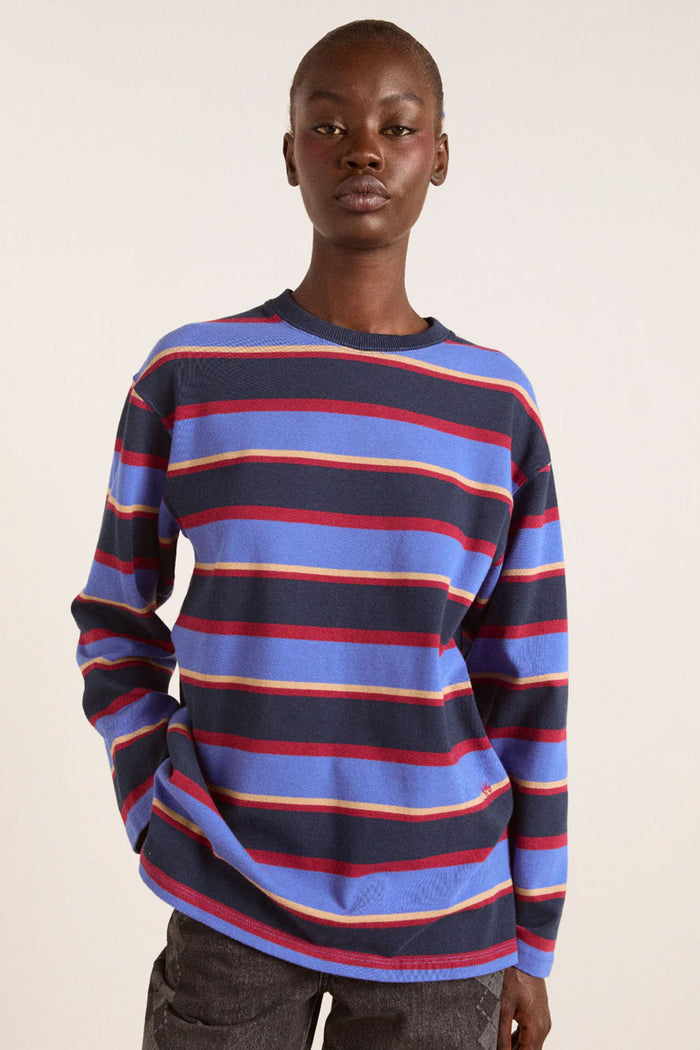 Person wearing a striped sweater with blue, red, and yellow colors on a plain background