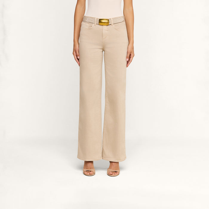 A person wears the Alicent Wide-Leg Jean in beige, paired with a light-colored belt featuring a gold buckle and open-toe sandals. The photo is taken against a plain white background, showing the outfit from the shoulders down.