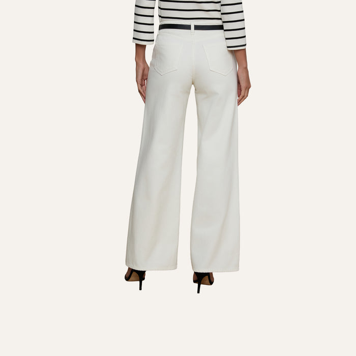A person is shown from the back against a plain background, wearing high-rise Alicent Wide-Leg Jean in white paired with a black-and-white striped top and black heels.
