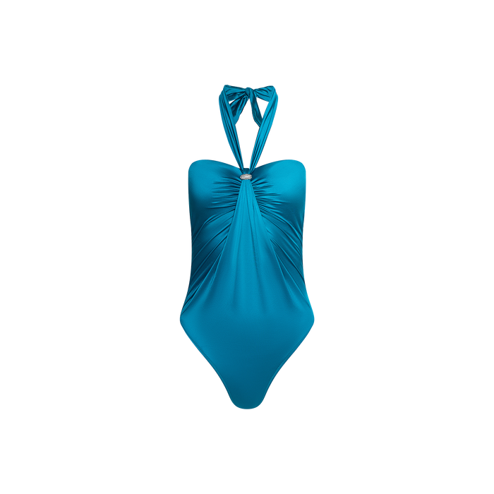 The Althea Bandeau One-Piece Swimsuit features a teal blue hue with a ruched front, central metal ring detail, and halter neck ties. Crafted from UPF 50 swimwear fabric for added sun protection, it is displayed on a plain white background.
