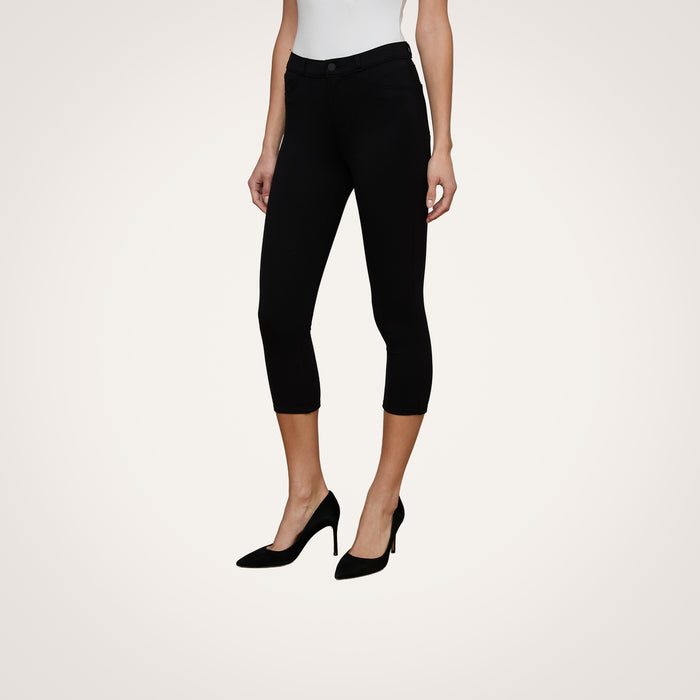 A person wearing the Amaris Pedal Pusher—black, body-hugging pants—paired with a white top and black high heels stands against a plain light background.