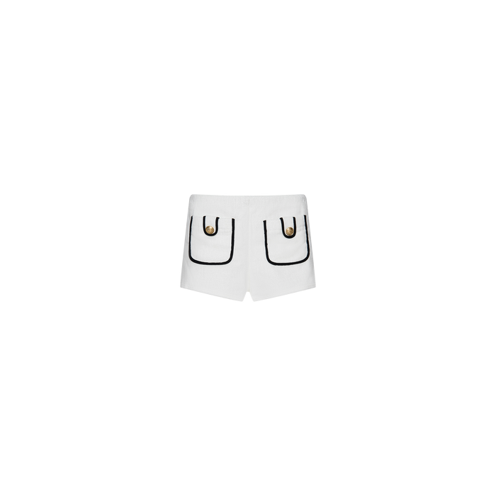The Amiya Cover-Up Short features white terrycloth fabric with two front pockets, each accented by black trim and a decorative gold button. Designed in a clean, minimalistic hot short style, these shorts are perfect for poolside lounging and are showcased against a plain white background.