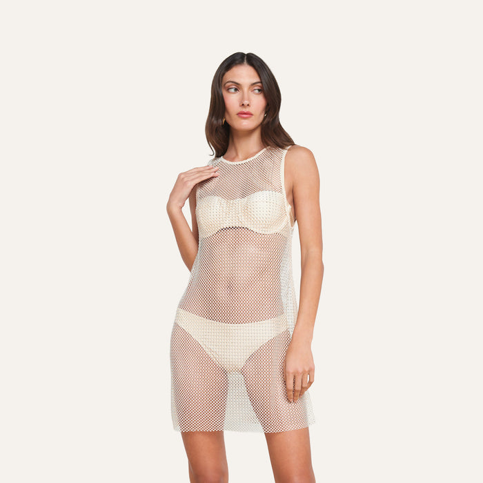 A woman stands wearing the Angela Mesh Cover-Up Dress over a cream bra and underwear set, looking to the side against a plain light background.