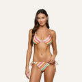 A woman stands and smiles, wearing the Annabelle Triangle Bikini Top featuring colorful retro-inspired stripes and an adjustable triangle silhouette, paired with matching side-tie bottoms, against a plain light background.