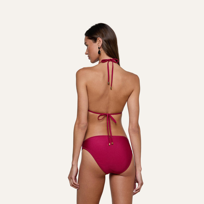 A woman is seen from behind wearing the Annabelle Triangle Bikini Top in maroon, featuring adjustable tie straps. She stands against a plain light background with her long brown hair down and black earrings.