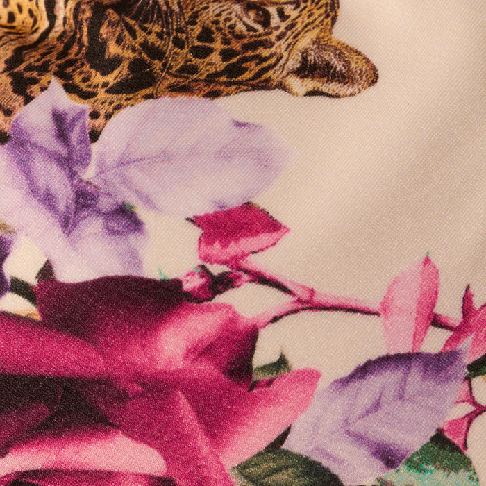 The Annabelle Triangle Bikini Top showcases a jungle leopard print, highlighting the leopard’s face framed by vibrant purple and pink flowers with green leaves on a light background.