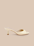 A single Arleen Kitten-Heel Mule in cream-colored leather, featuring an open toe and a sleek kitten heel, displayed on a beige background.