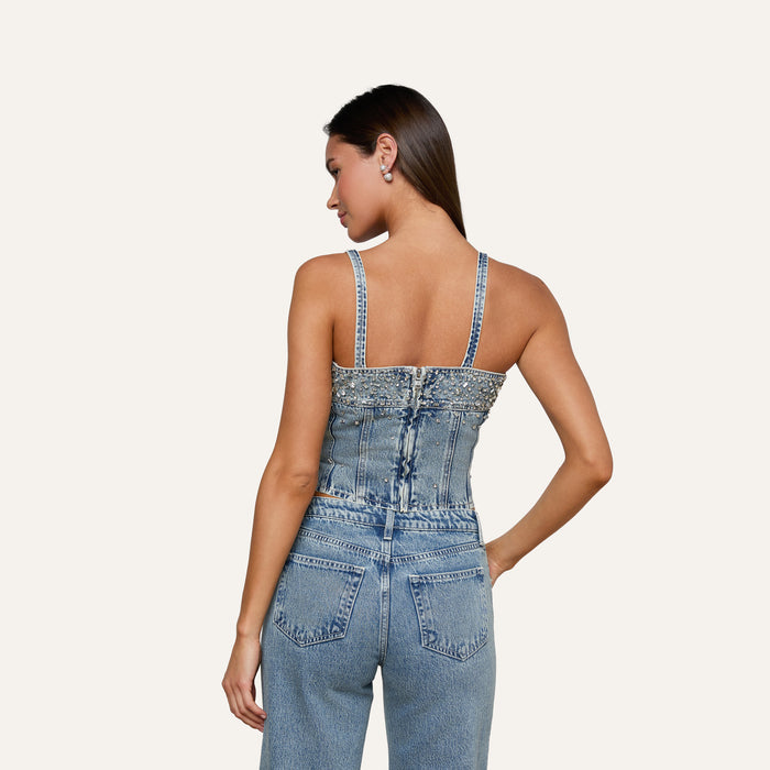 Woman with long dark hair, wearing the Arlin Embellished Tank and high-waisted blue jeans, standing with her back to the camera against a plain light background.