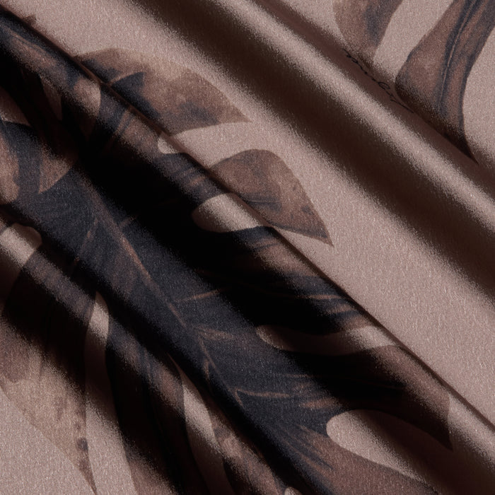 Close-up of the Asami Chain One-Shoulder Blouse featuring a textured fabric with a dark brown leaf pattern and diagonal shadows, creating a soft, flowing appearance reminiscent of satin.