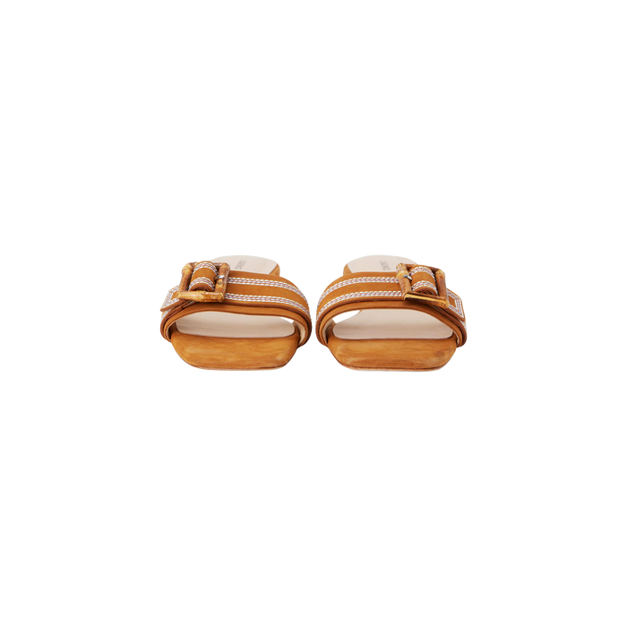 The Aurelie Buckle Sandal, a pair of brown suede slide sandals featuring bamboo buckles and white stitching, is shown from the front on a plain white background.