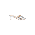 The Aveline Kitten-Heel Sandal is a silver mule crafted from metallic leather, featuring crisscross straps and a strappy vamp with an open toe, shown in a side view against a white background.