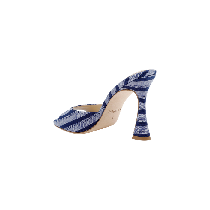 The Avery Open-Toe Mule is a denim high-heeled mule with a flared heel, featuring blue and white diagonal stripes and an open-toe design, shown on a white background.