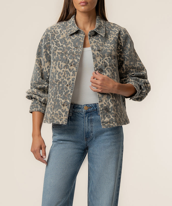 Tan and brown leopard print denim jacket with collar, button front, and chest pockets worn over white top.