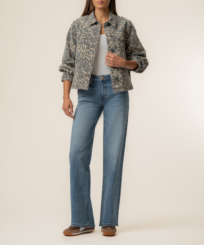 Tan and brown leopard print denim jacket with collar and front button closure worn over white top and blue jeans.