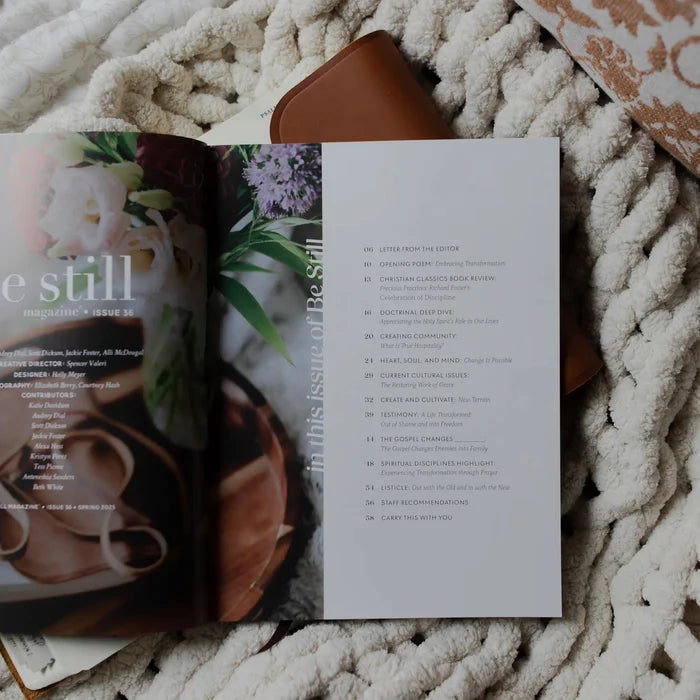 Be Still Issue 36 Magazine opened to the table of contents laying on an open bible on a white knitted blanket
