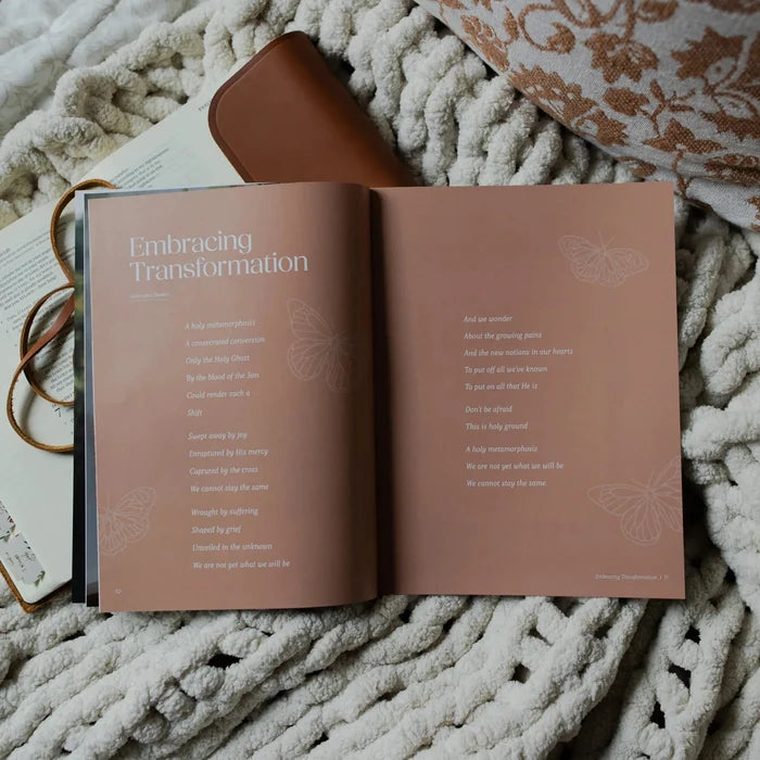 Be Still Issue 36 Magazine opened to the Embracing Transformations page laying on an open bible on a white knitted blanket