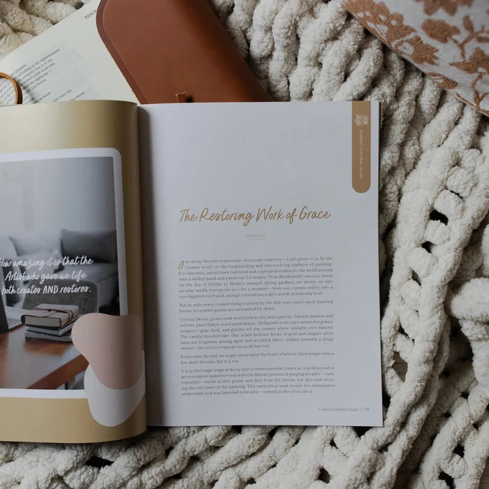 Be Still Issue 36 Magazine opened to the Restoring Work of Grace page laying on an open bible on a white knitted blanket
