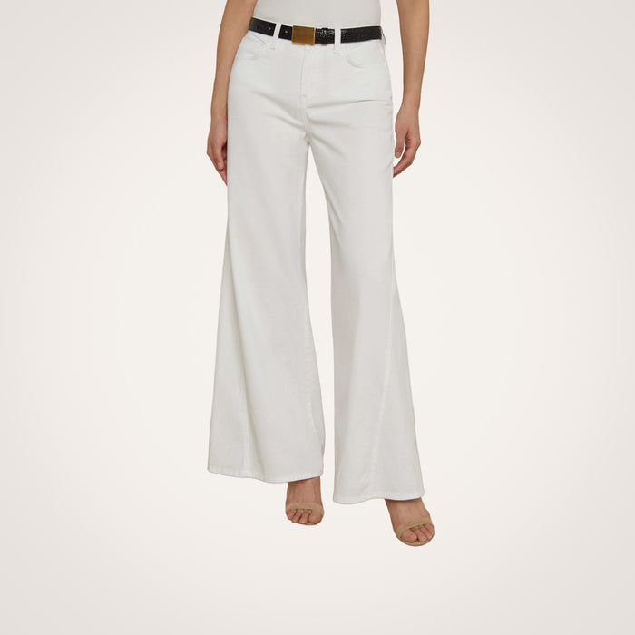 A person is shown from the waist down, wearing the Beau Wide-Leg Jean in white paired with a black belt and open-toed heels, standing against a plain light background. The upper body and face are not visible.