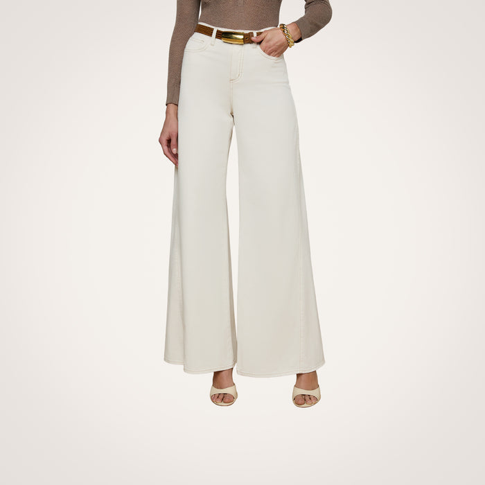 A person wearing the Beau Wide-Leg Jean in cream stretch cotton twill, paired with a brown long-sleeve top, beige heeled sandals, and a gold bracelet, standing against a plain white background.
