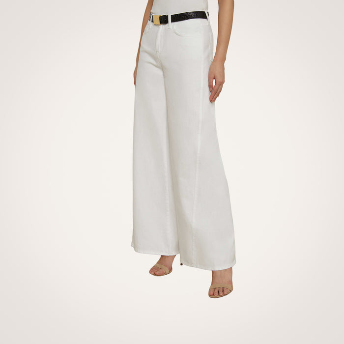 A person wearing the Beau Wide-Leg Jean in white, styled with a black belt and open-toe heels, stands against a plain, light background.