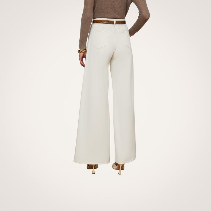 A person wearing the Beau Wide-Leg Jean in high-rise, wide-leg white stretch cotton twill, paired with a brown long-sleeve top and heeled shoes, shown from the back against a plain white background.