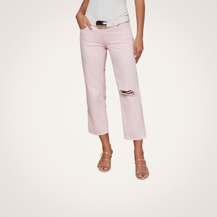 A woman wearing the Blaine Cropped Stovepipe Jean in pastel lilac with a knee rip, styled with a white belt, white top, and nude strappy heels, stands against a plain white background.