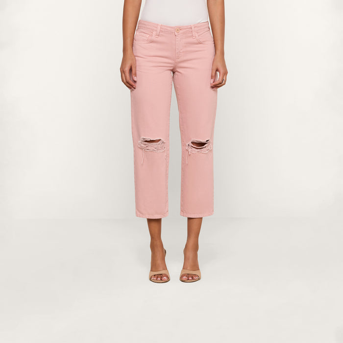 A person wearing the Blaine Cropped Stovepipe Jean in light pink with a ripped, low-rise, straight-leg fit and open-toed heels stands against a plain white background.