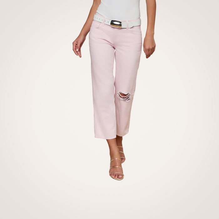 A woman models the Blaine Cropped Stovepipe Jean in light pink with ripped detailing, paired with a white belt, a white top, and strappy nude sandals against a plain white background. Her head is not visible in the image.
