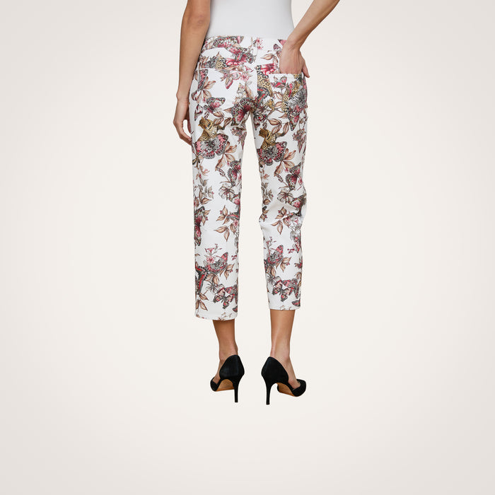 A person is seen from the back wearing the Blaine Cropped Stovepipe Jean in white with a floral print, styled with black high heels and one hand in a pocket, against a plain light background.
