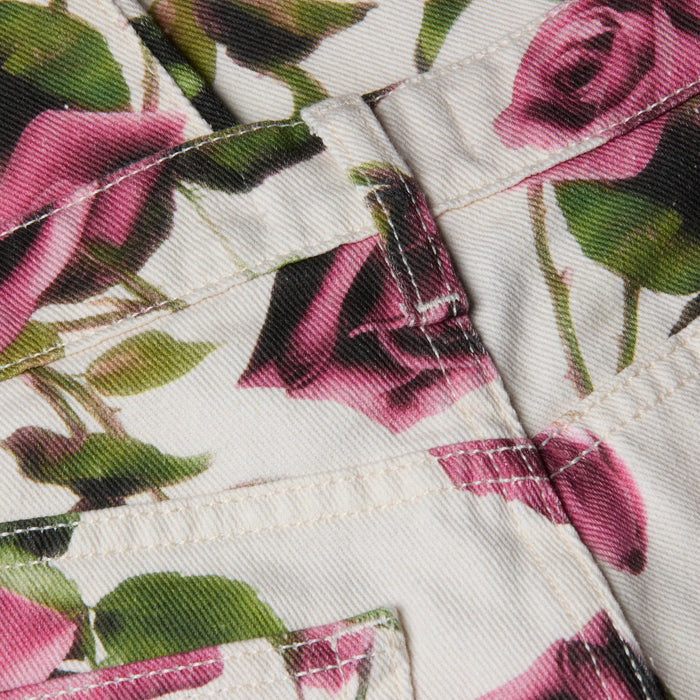 Close-up of fabric with a white background and a rose print featuring pink floral patterns, visible stitching, and seams—likely part of the Blaine Cropped Stovepipe Jean.